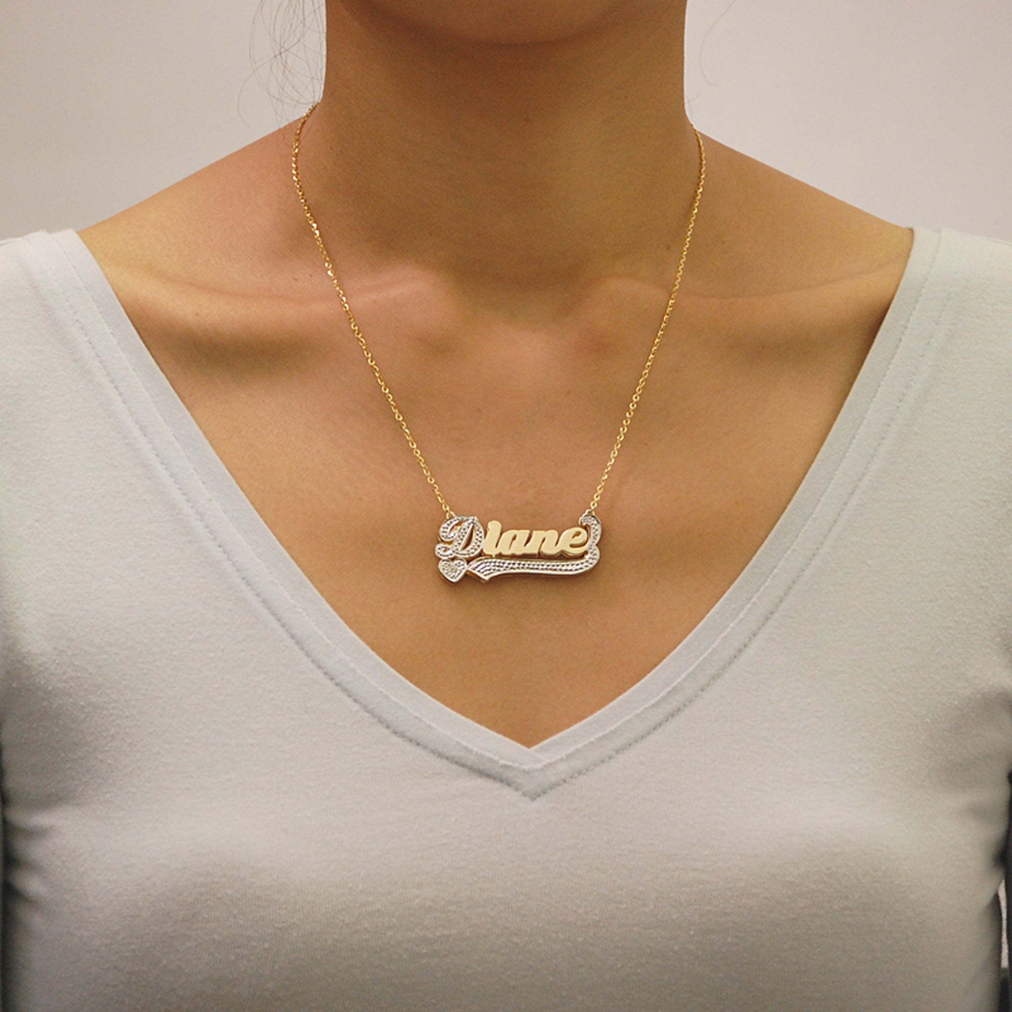 Model wearing a personalized 14K gold 3D double plate custom nameplate pendant on a gold Cuban chain.