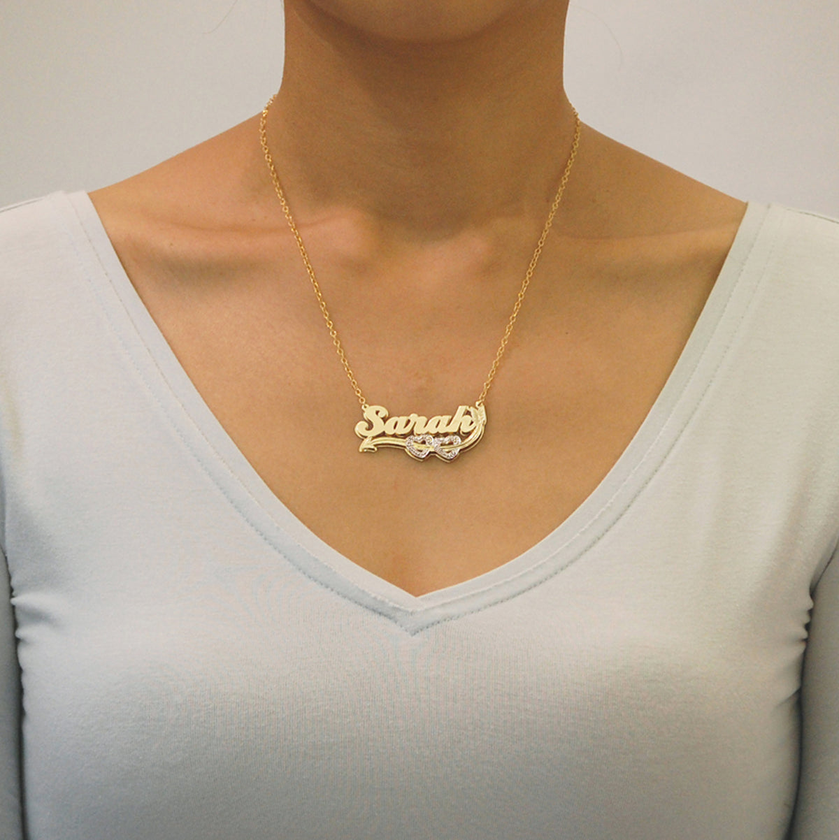 Model wearing a handcrafted custom solid 14K gold 3D double plate nameplate necklace attached to a rolo chain.
