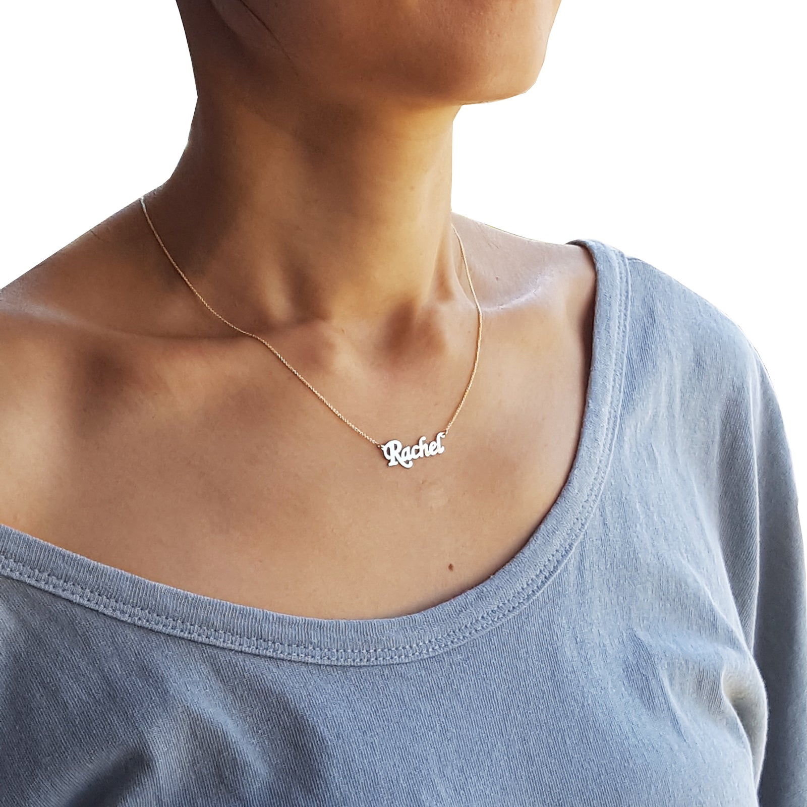 Model wearing custom 1-inch dainty gold cursive name necklace styled with a blue top.
