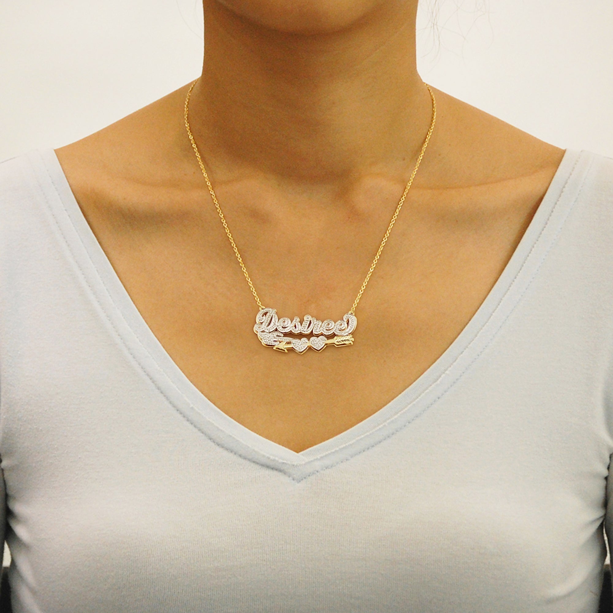 Woman wearing custom solid gold 3D Cupid arrow diamond name pendant necklace on a Figaro chain.