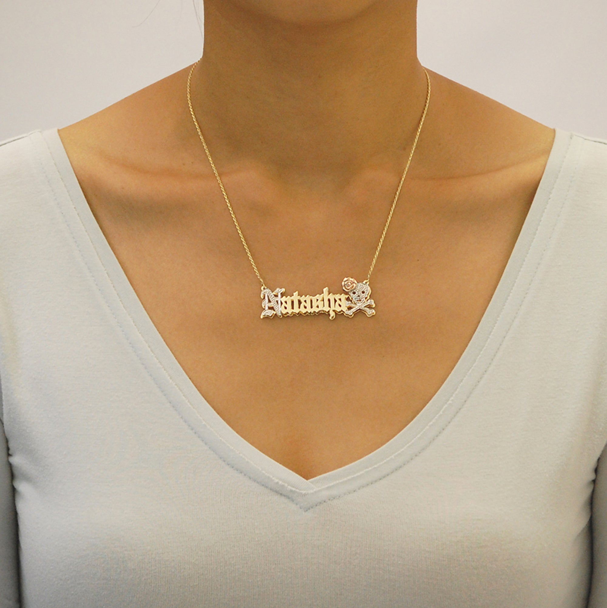Woman wearing a personalized 10k solid gold Old English nameplate necklace with skull crossbones accent.
