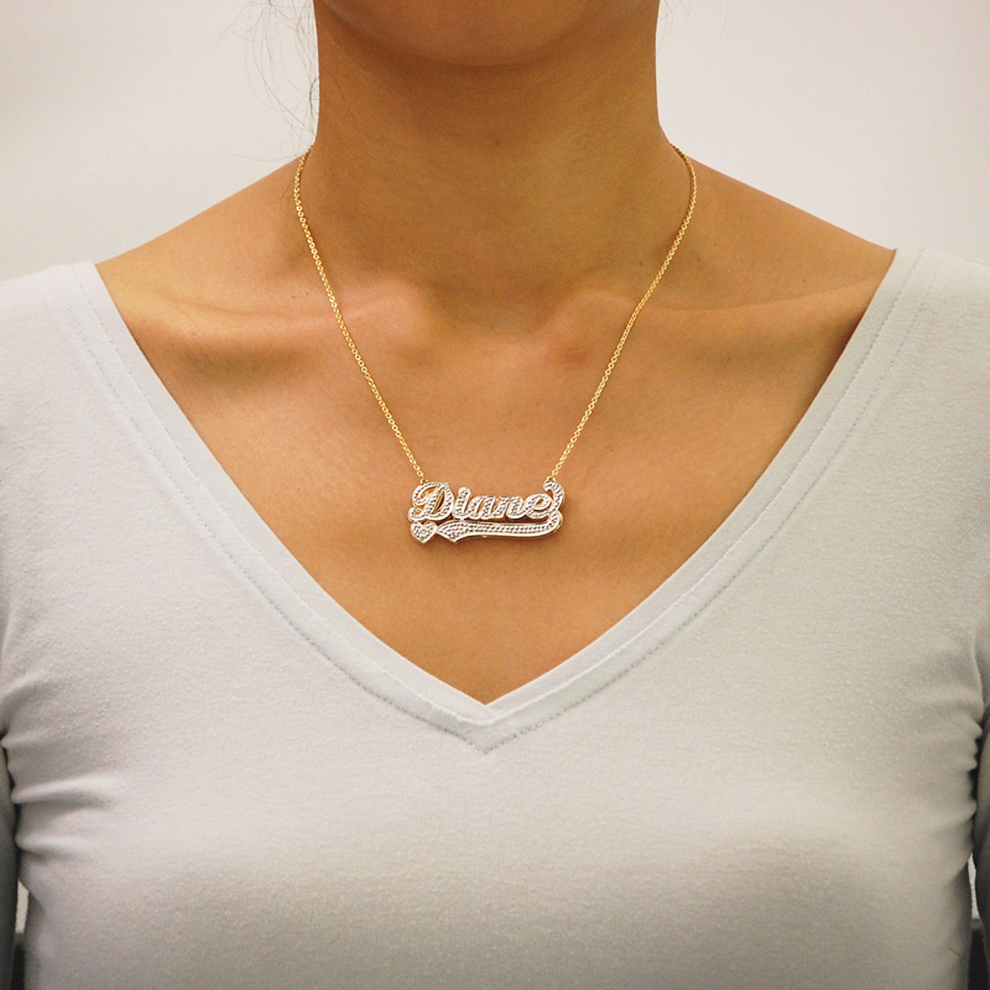 Model wearing personalized 10k solid gold 3D double plate diamond name necklace with Cuban chain.