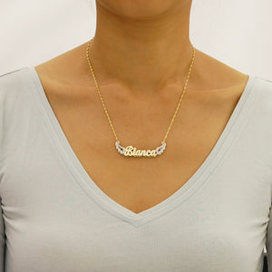 Model wearing personalized 14k gold angel wings 3D nameplate necklace.