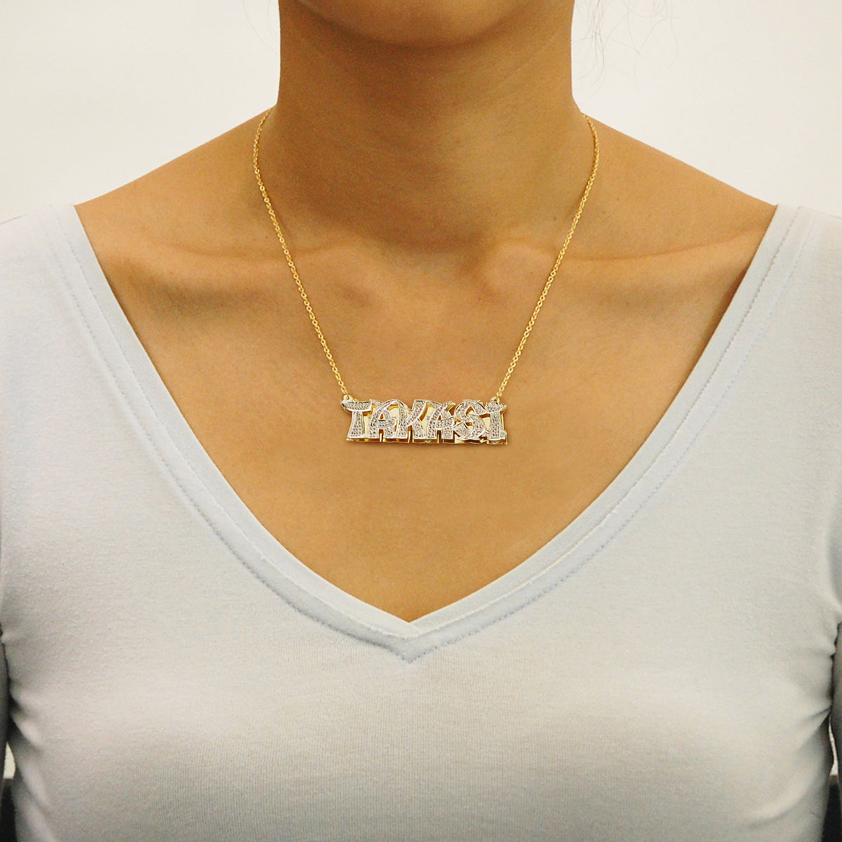 Model wearing a personalized gold 3D double plate nameplate pendant on a solid gold Cuban link chain.