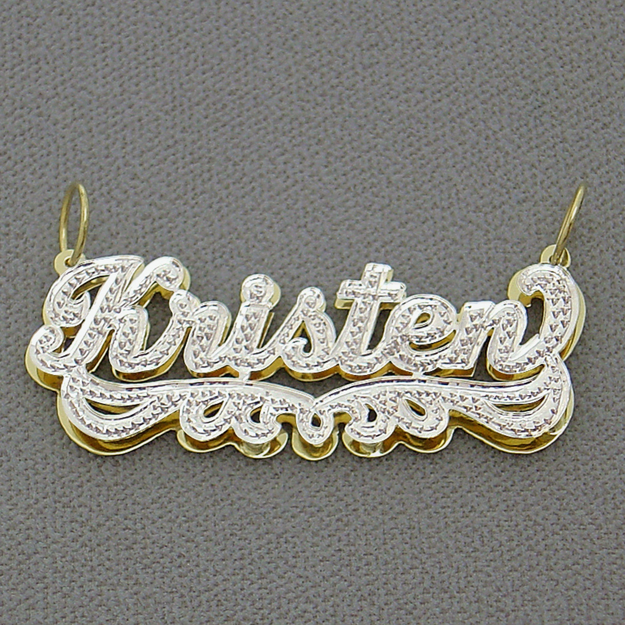 Close-up of hand-carved rhodium diamond accent details on 14k gold custom name pendant.