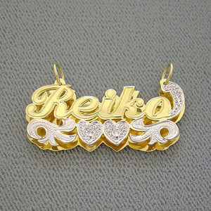 Close-up of hand-carved diamond accents and rhodium-plated heart detail on a solid gold 3D double plate name pendant.