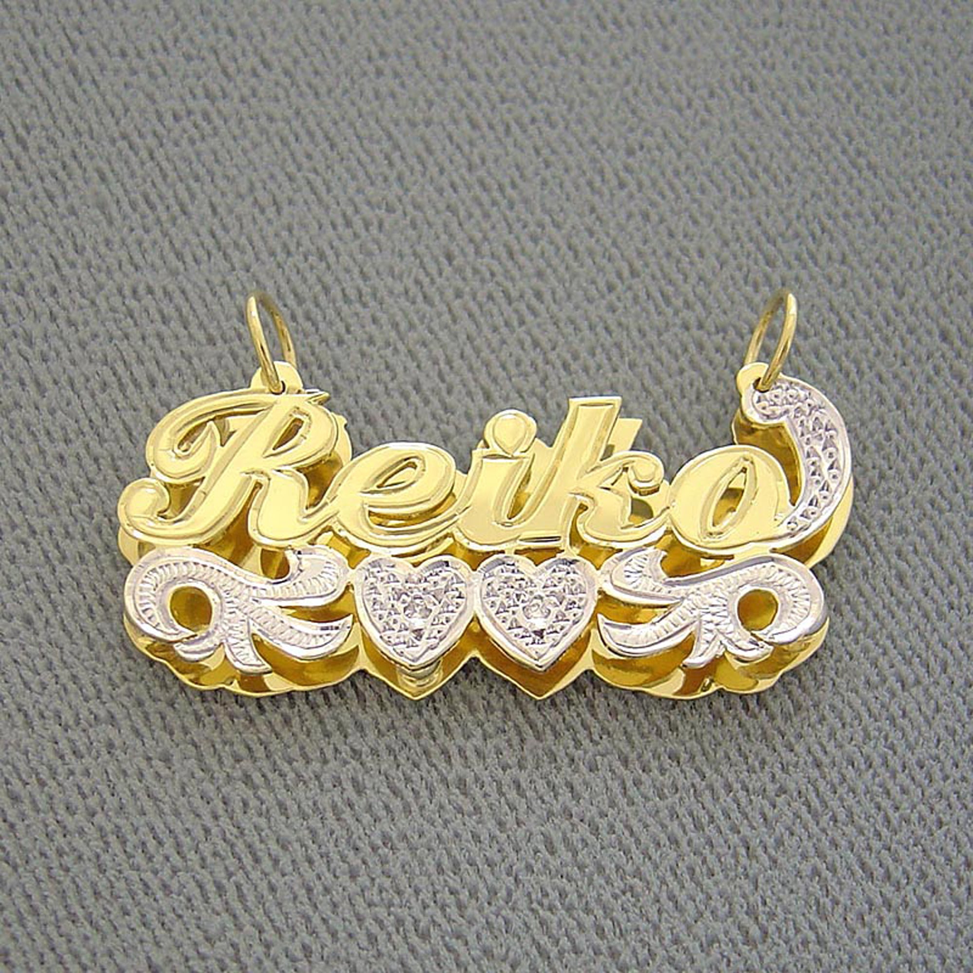 Close-up of hand-carved diamond accents and rhodium-plated heart detail on a solid gold 3D double plate name pendant.