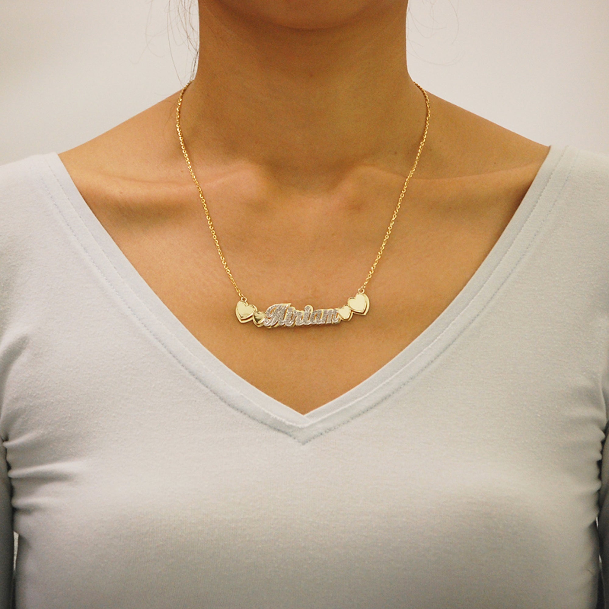 Woman wearing custom 14k solid gold double plate name necklace with heart accent