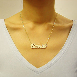 Woman wearing a custom 10K solid gold 3D double plate cursive nameplate necklace paired with a gold figaro chain.