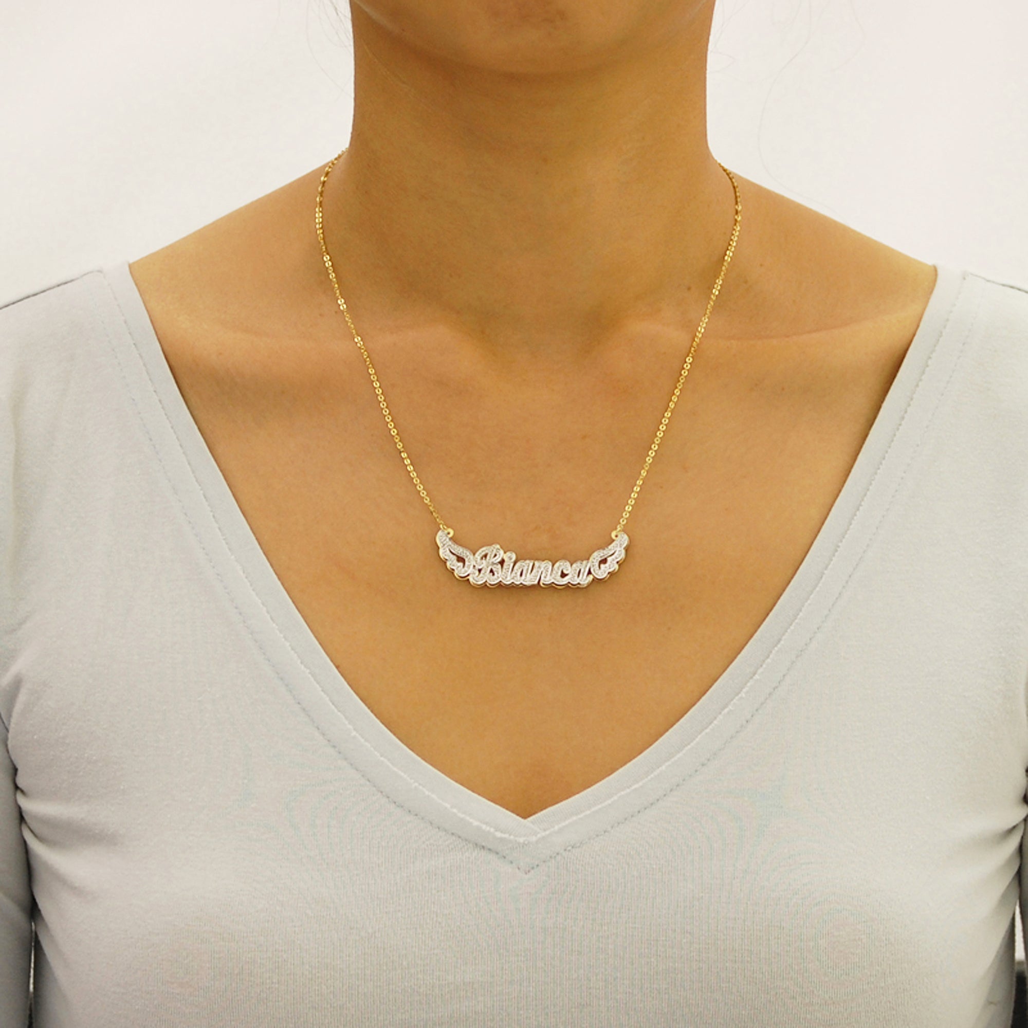 Woman wearing a handcrafted solid gold 3D angel wings nameplate necklace.