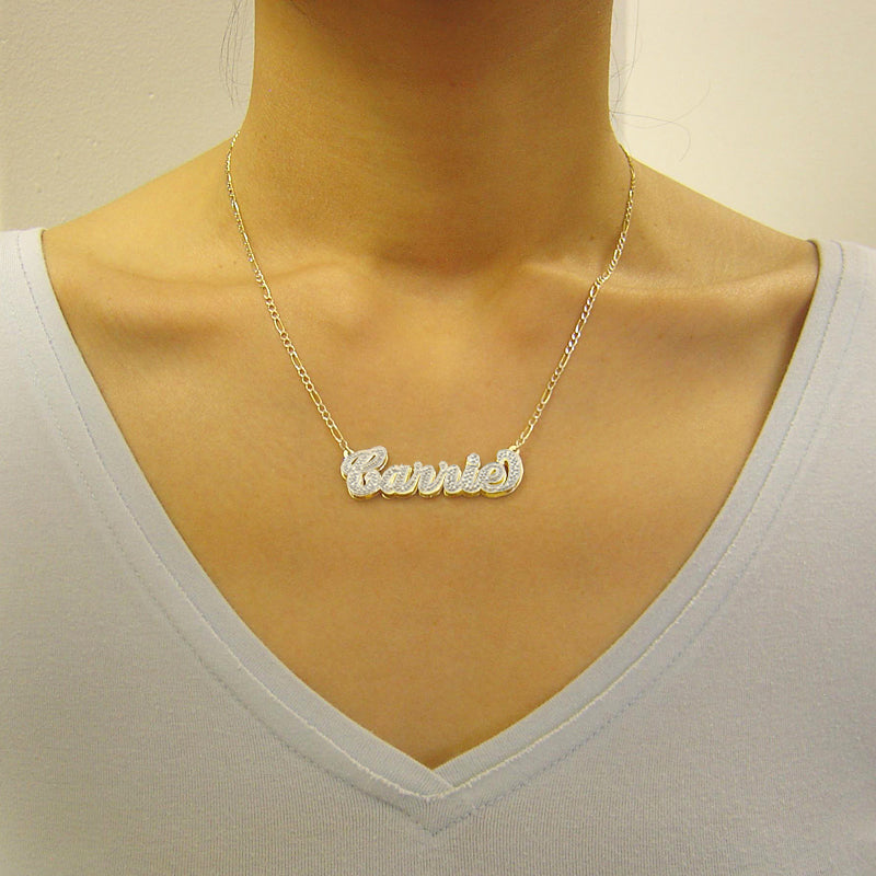 Woman wearing a custom 3D gold double plate nameplate pendant necklace styled on a gold Figaro chain.