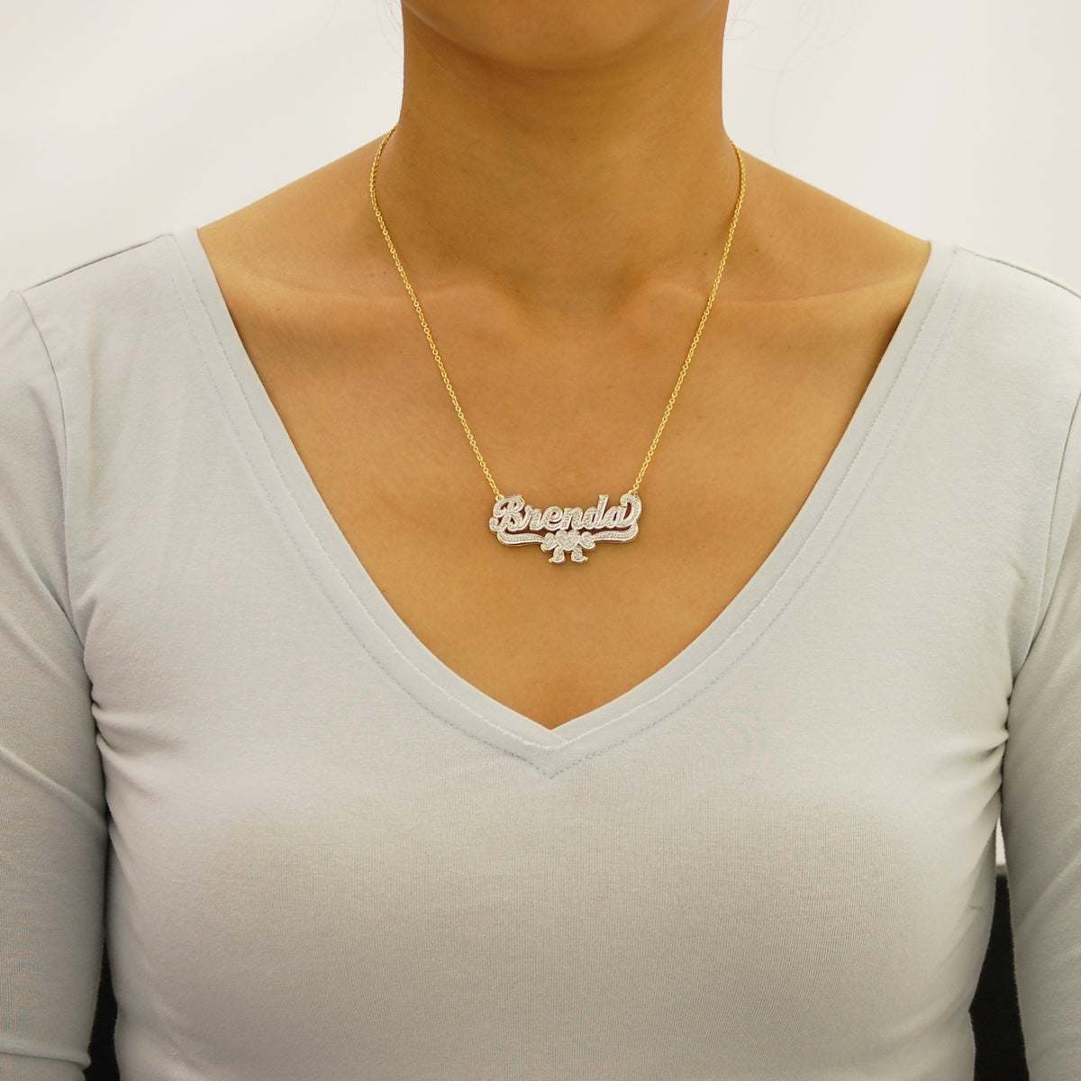 Woman wearing a custom 10k or 14k solid gold personalized 3D nameplate necklace with ribbon charm.