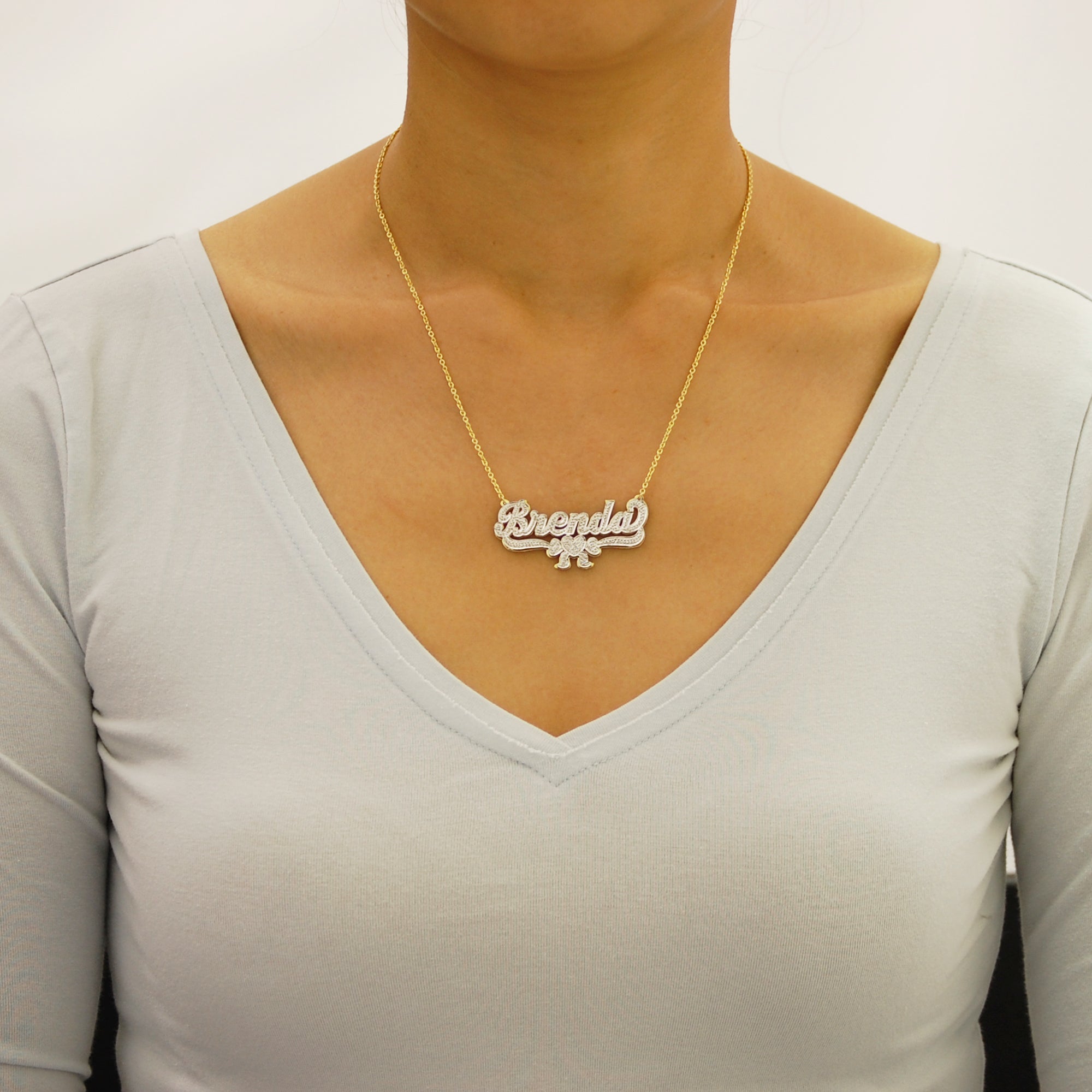 Woman wearing a custom 10k or 14k solid gold personalized 3D nameplate necklace with ribbon charm.